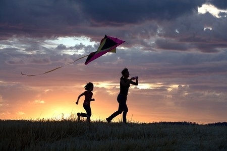 happy people running outside with a kite 